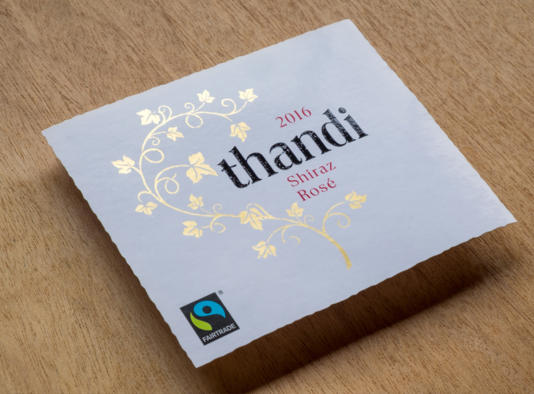 Finished Thandi Shiraz Rosé wine label with gold foil on wood surface