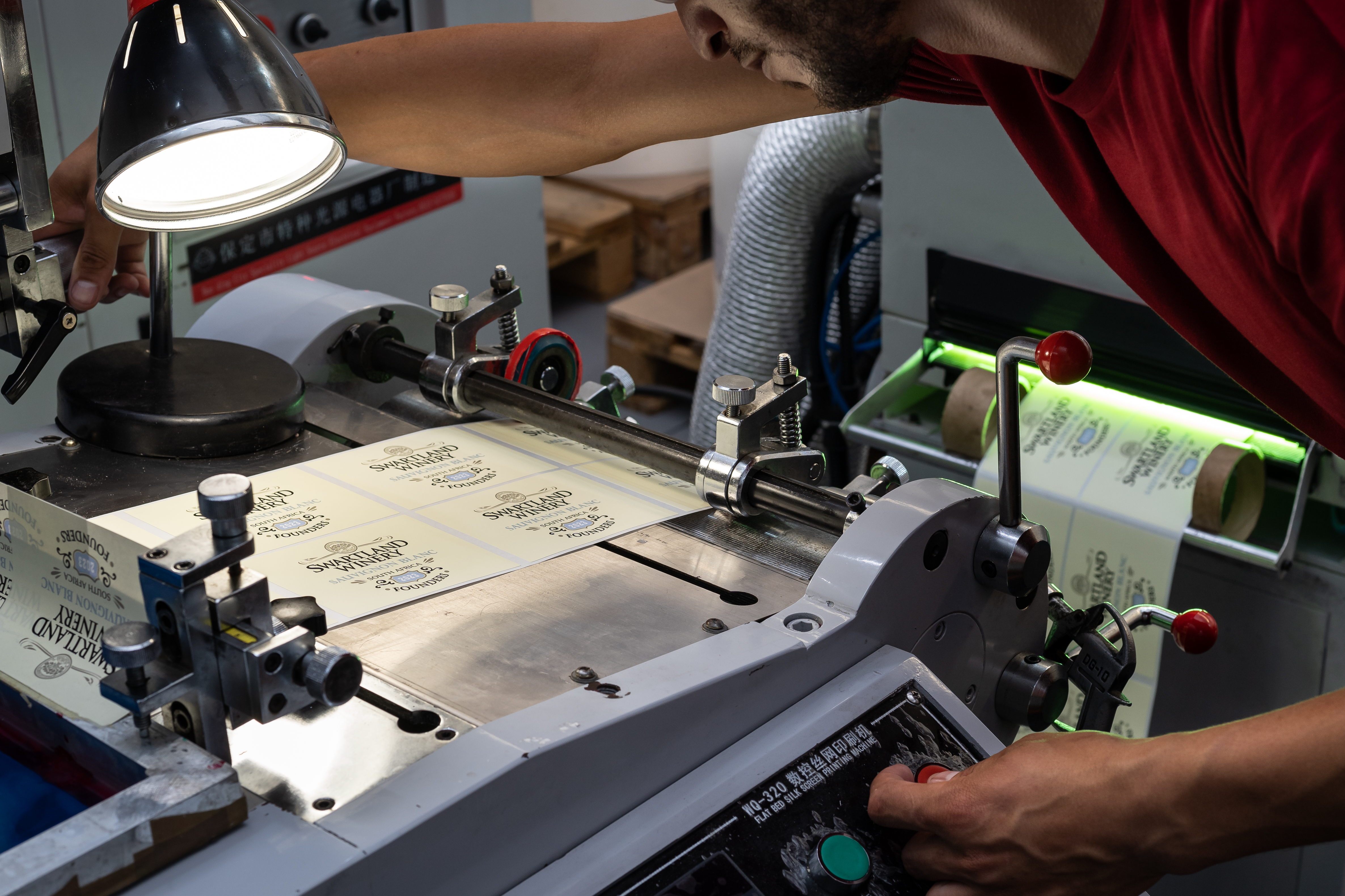 Technician at silkscreen press printing Swartland Winery Sauvignon Blanc labels